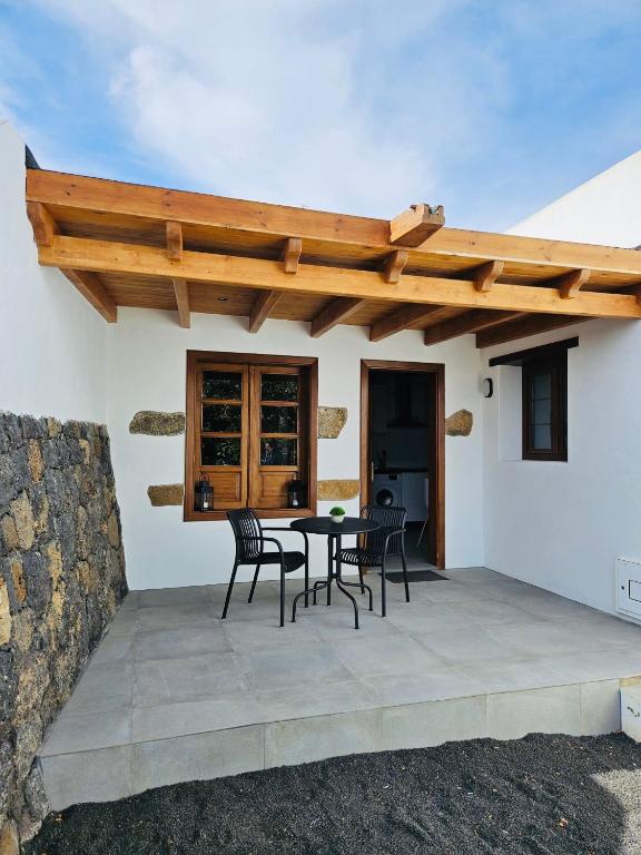 a patio with a table and chairs under a wooden roof at Casa Celi in Teguise