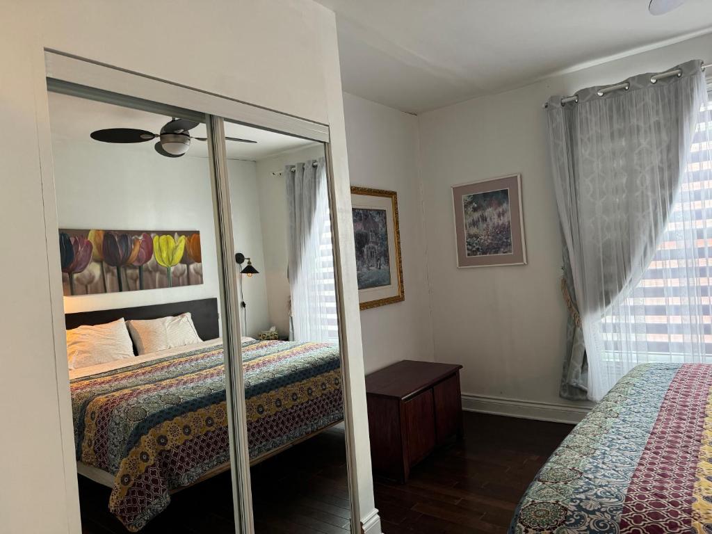 ein Schlafzimmer mit einem Spiegel, einem Bett und einem Fenster in der Unterkunft Le 2316 in Saint-Hyacinthe