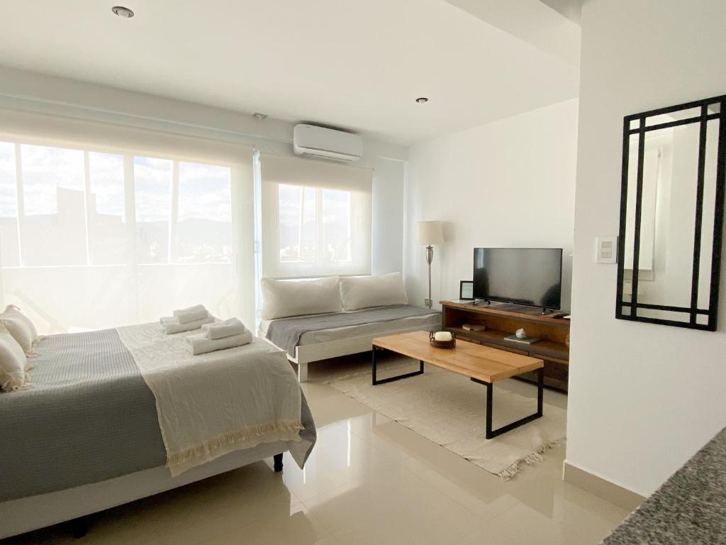 una camera da letto con un letto, un divano e una TV di Delta Boutique Loft, en el centro de Salta, p/ 3 a Salta