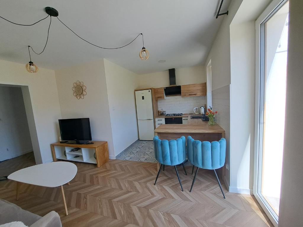 ein Wohnzimmer mit 2 blauen Stühlen und eine Küche in der Unterkunft Zwierzyniecki Zakątek in Zwierzyniec