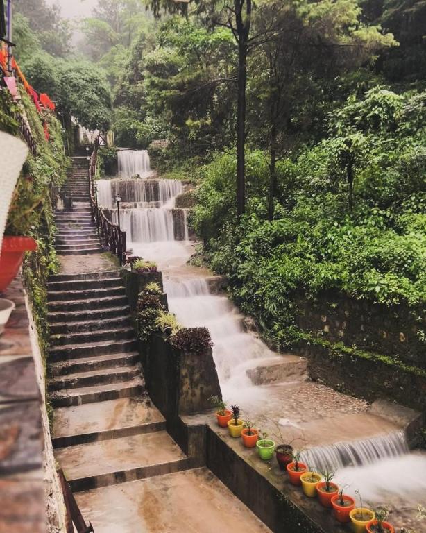 a stairway leading to a waterfall with colorful pots at Little Heaven - Cabin 2 in Rājpur