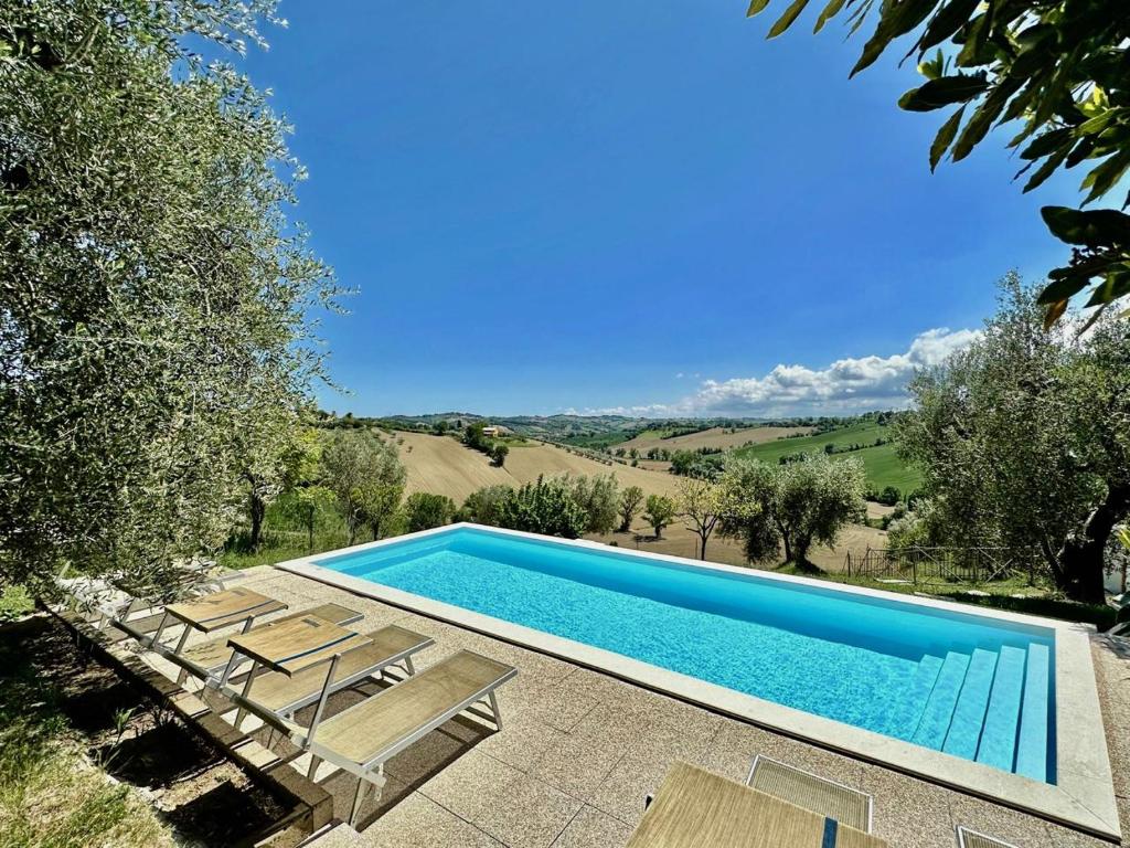 una piscina con sedie a sdraio e una piscina di Casale Casini Soccorso a Senigallia