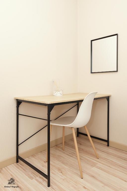 a desk with a white chair in front of a wall at Les Jardins d&#39;Hermès in Troyes