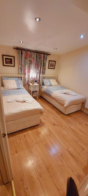 two beds in a room with wooden floors at Beautiful Apartment in Bristol