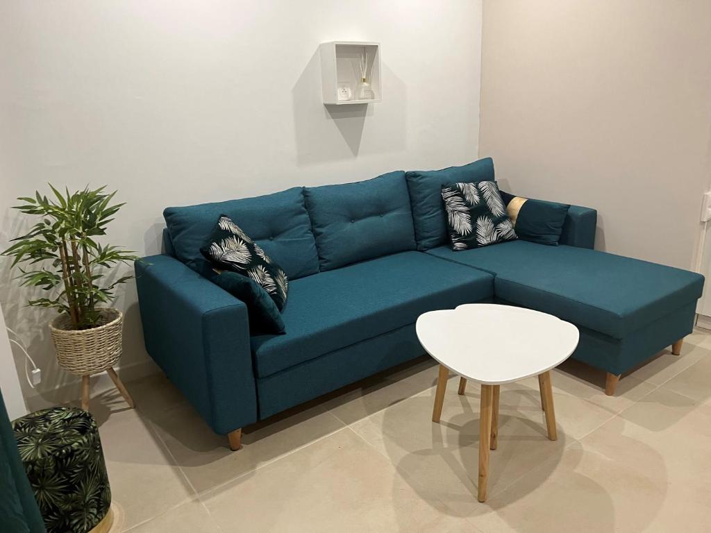 un canapé bleu dans un salon avec une table dans l'établissement Maison de 40m2,Clim, Wifi, jardin et parking, à Marseille