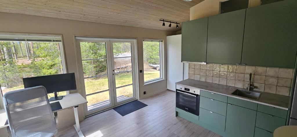 eine Küche mit grünen Schränken und einem Schreibtisch mit einem Computer in der Unterkunft Lägenhet Ateljén in Hudiksvall