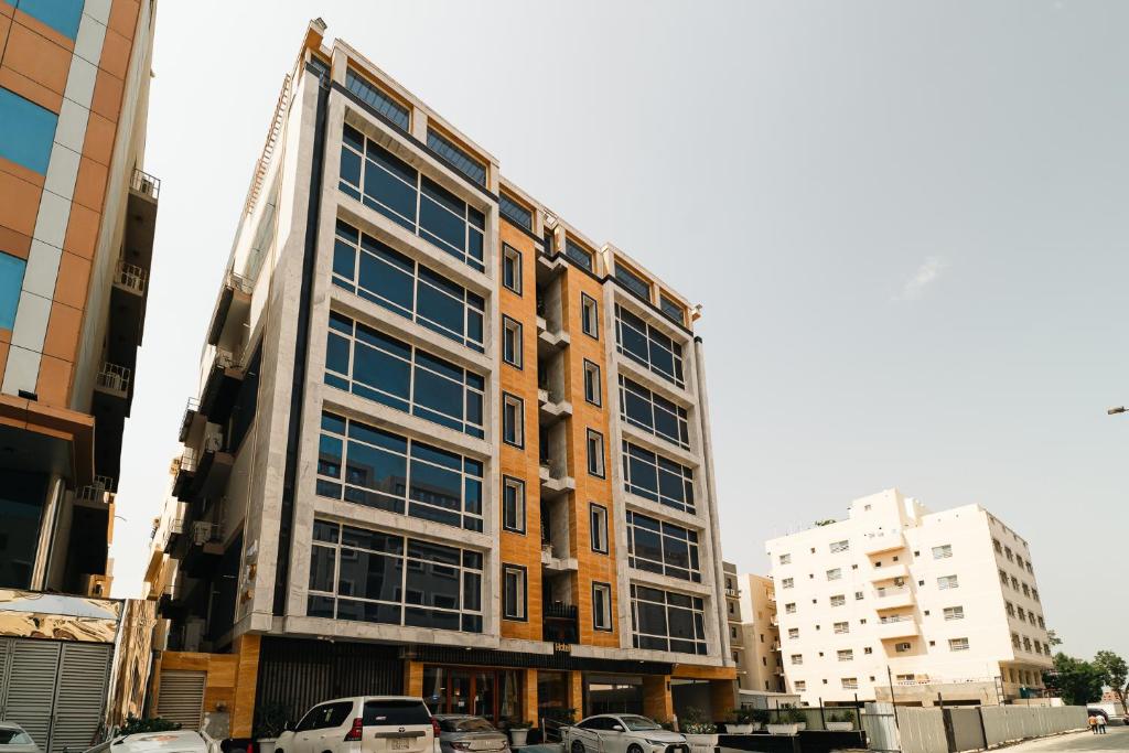 wysoki budynek z samochodami zaparkowanymi przed nim w obiekcie Rooms Hotel w mieście Dżudda