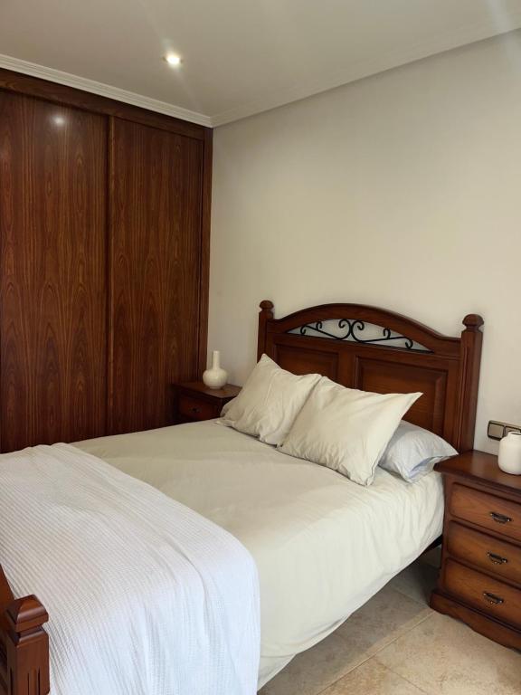 una camera con letto bianco e testiera in legno di Apartamento Verano a Mugardos