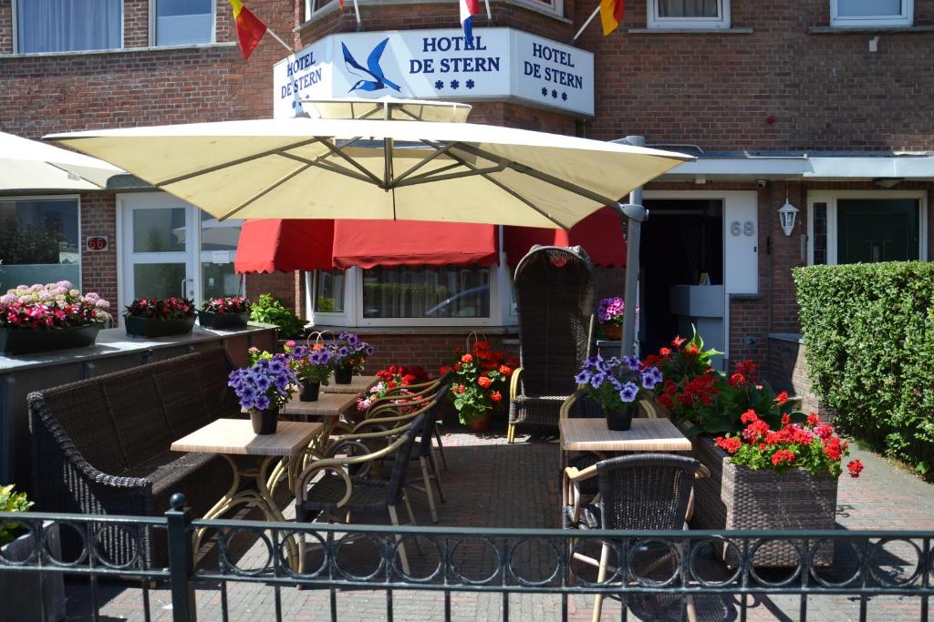 ein Restaurant mit Tischen, Stühlen und einem Sonnenschirm in der Unterkunft Hotel De Stern in Scheveningen