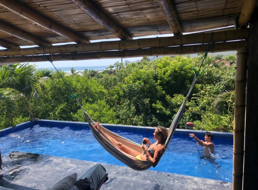 a girl and two boys in a hammock by a pool at Hermanos Perdidos Surf in Las Tunas