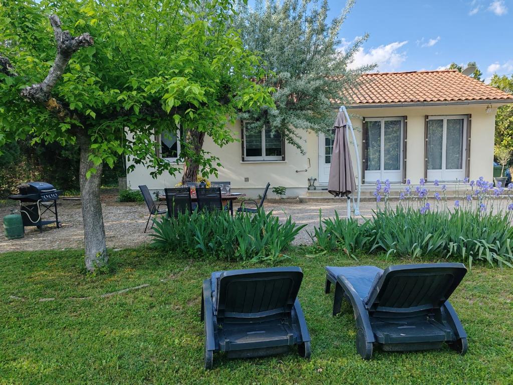 zwei Stühle und ein Regenschirm vor einem Haus in der Unterkunft Maison au calme avec jardin et local vélo in Jonquières