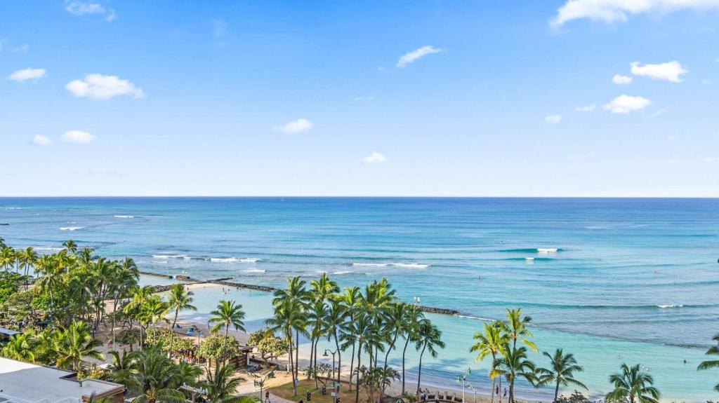 a view of a beach with palm trees and the ocean at Luxury Oceanfront 2 Bedroom Apartment at Waikiki Beach Tower in Honolulu