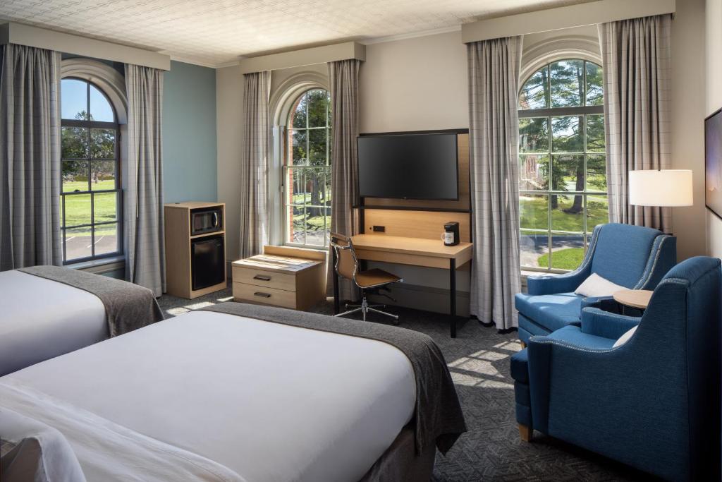 a hotel room with a bed and a desk and a tv at Hotel Ursa in Orono