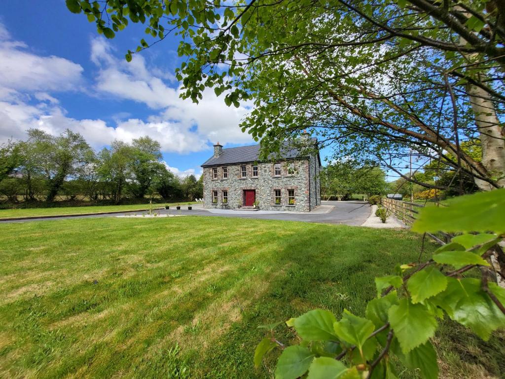 uma antiga casa de pedra com um grande campo de relva em Reeks Country House em Killarney