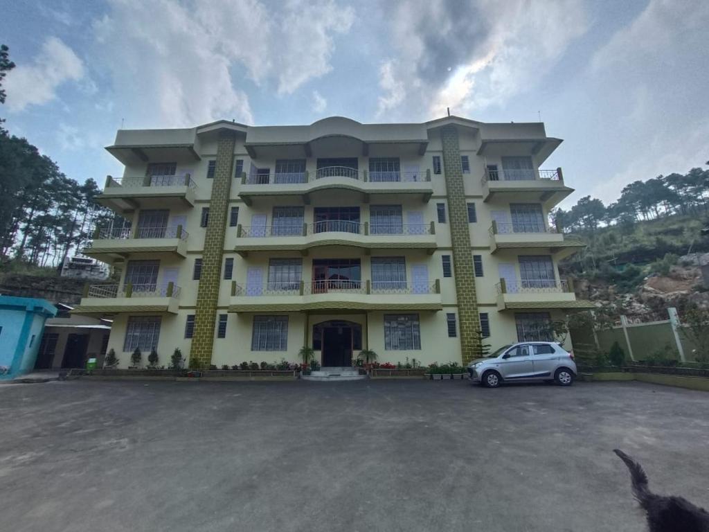 ein großes Gebäude mit einem davor geparkt in der Unterkunft DAMEKI a unit of ME HOSPITALITY in Shillong