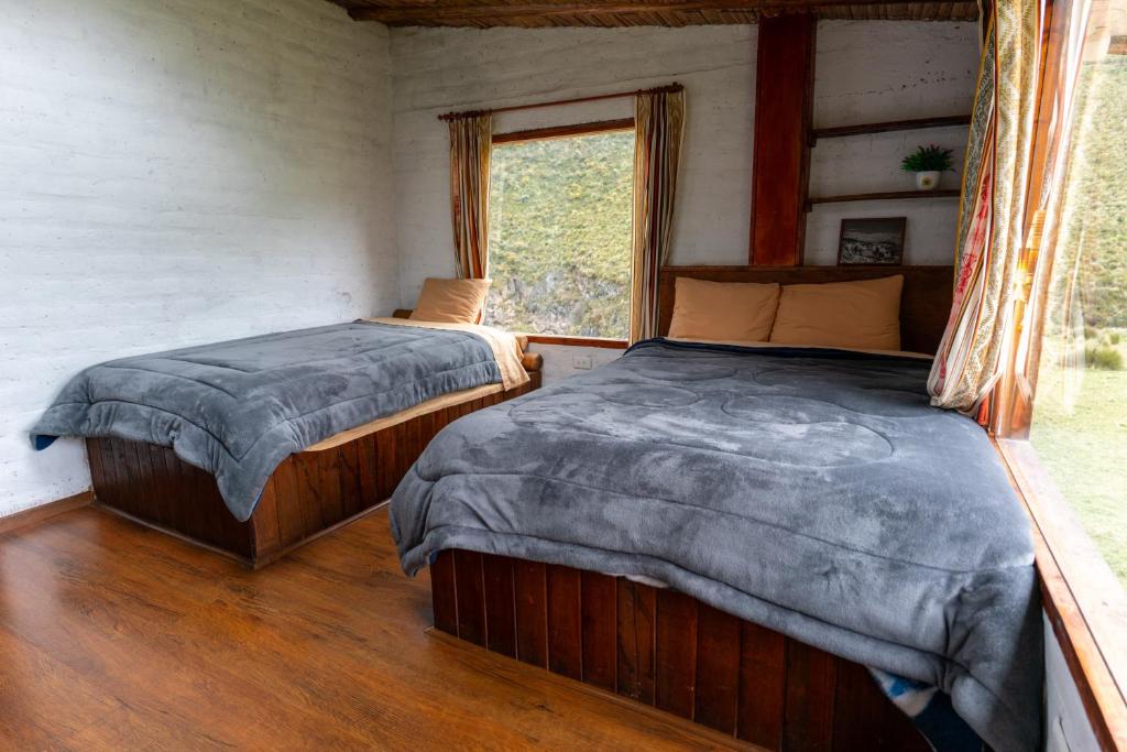 two beds in a room with a window at Chakana templo de montaña in Chimborazo