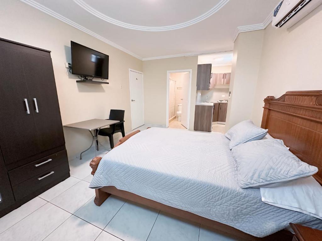 Dormitorio con cama, escritorio y TV en Suitesecu Guayaquil, en Guayaquil