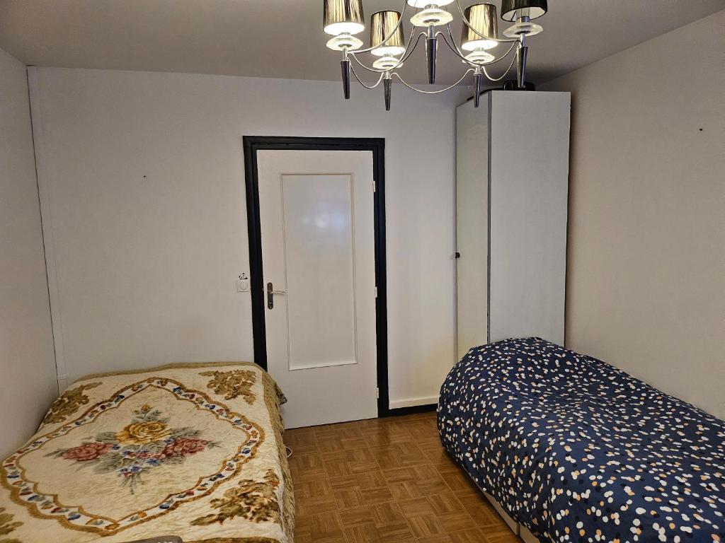 1 dormitorio con cama y lámpara de araña en chambre 5mn de paris, en Fontenay-sous-Bois