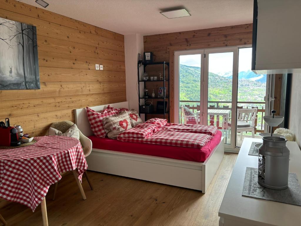 een slaapkamer met een bed en een tafel en een balkon bij Studio 22 Veysonnaz in Veysonnaz