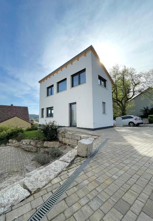 une maison blanche avec une voiture garée devant elle dans l'établissement Tiny House Wettelsheim, à Treuchtlingen