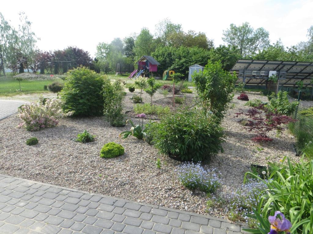 un jardin avec des plantes et une aire de jeux en arrière-plan dans l'établissement Dom z widokiem na jezioro, à Chrostkowo