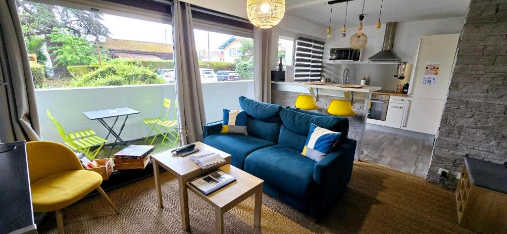 Il comprend un salon avec un canapé bleu et une cuisine. dans l'établissement Le Kalloé, à Thonon-les-Bains