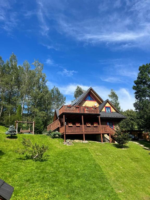 a large log cabin with a deck on a green field at Chata Valika Jezersko in Vígľaš