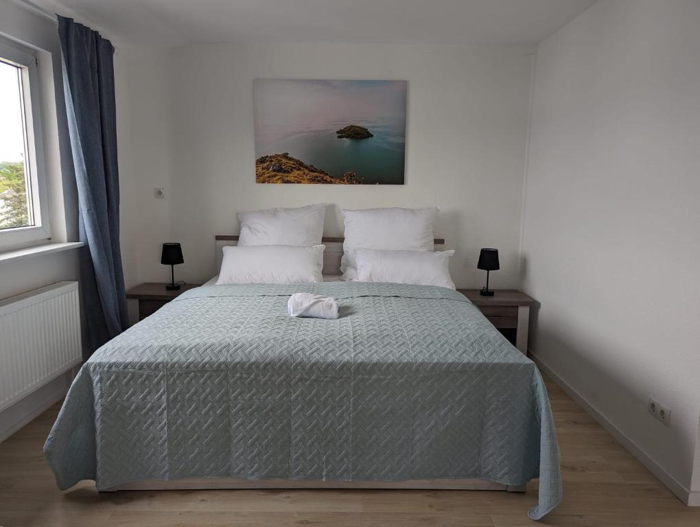 ein weißes Schlafzimmer mit einem Bett mit einer grauen Decke in der Unterkunft Hercules Horizon Apartment in Kassel