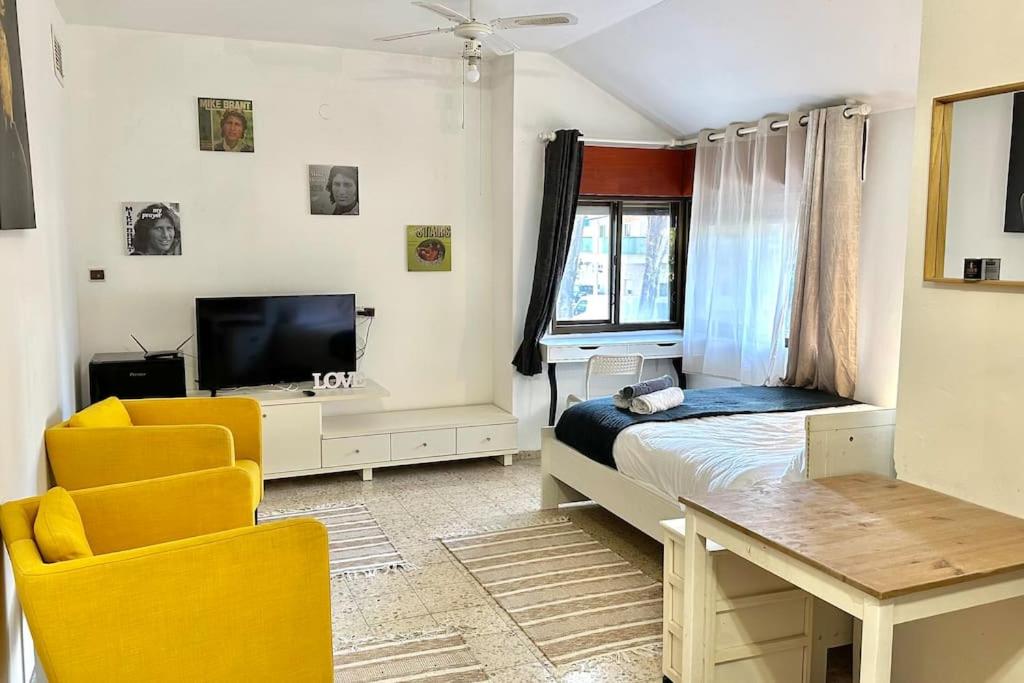 a bedroom with a bed and a table and chairs at Studio in the center with BBQ Patio and parking in Nahariyya