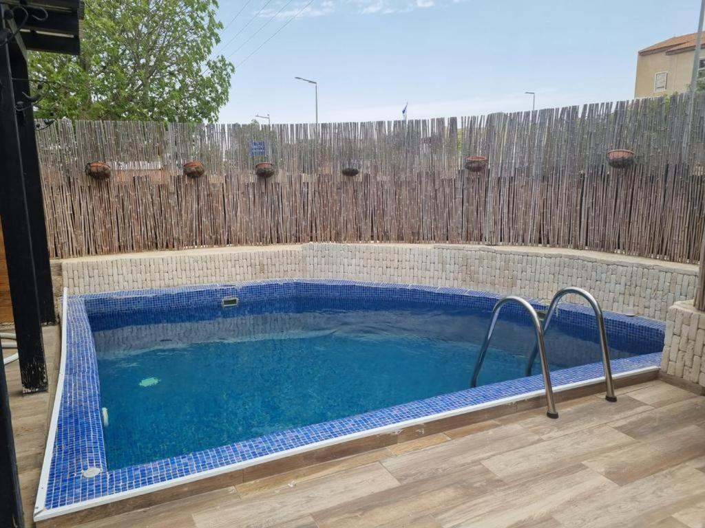 a swimming pool in front of a wooden fence at צימר רמון in Mitzpe Ramon