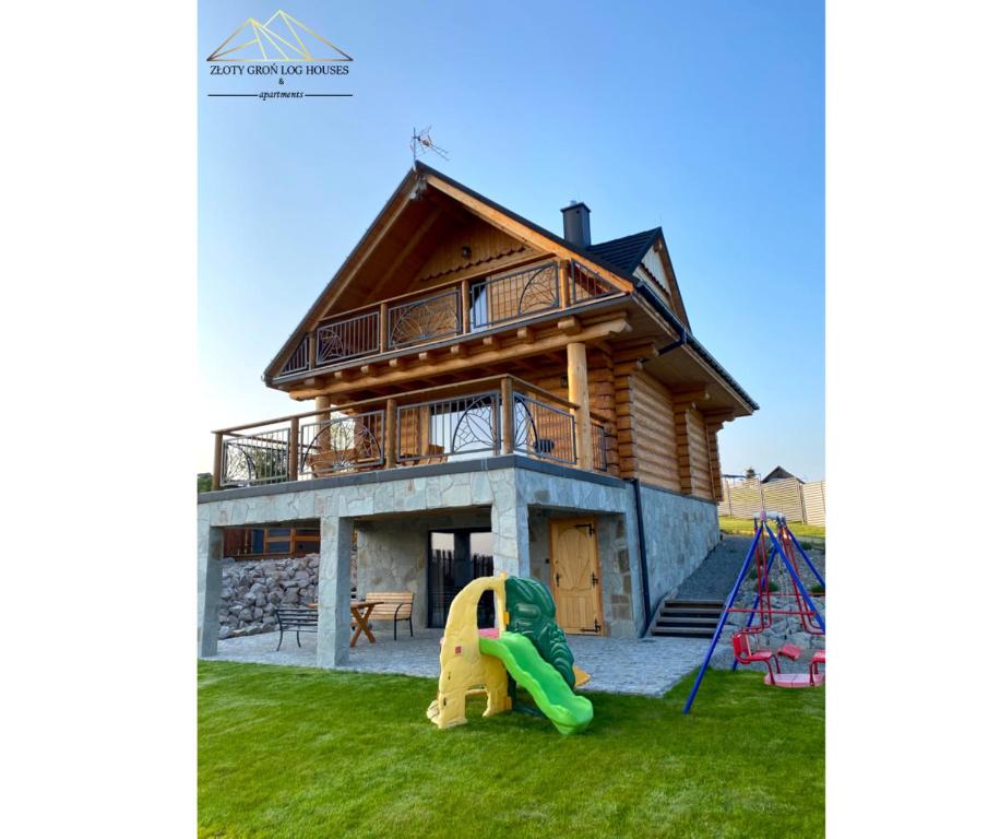 a log house with a slide and a playground at Złoty Groń log houses & apartments in Istebna