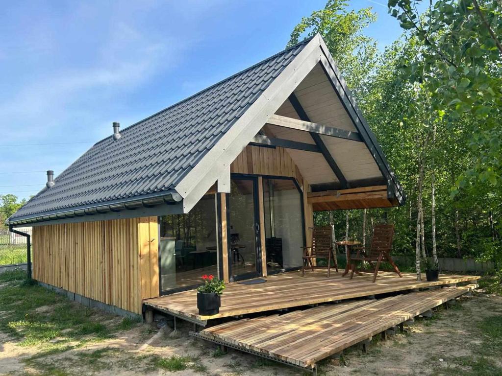 a small cabin with a wooden deck with a roof at Bajkowy Domek 2 nad rzeką Liwiec in Łochów