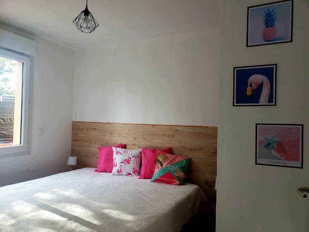 een slaapkamer met een bed met roze kussens en een raam bij les gites du parc animalier de ginasservis in Ginasservis