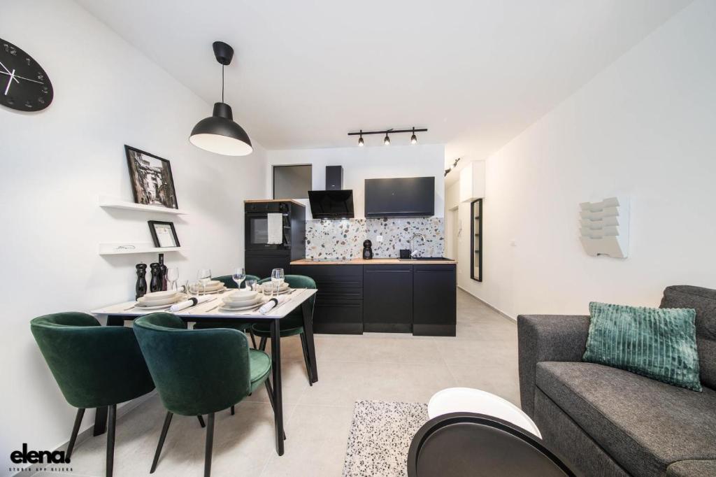 eine Küche und ein Wohnzimmer mit einem Tisch und grünen Stühlen in der Unterkunft Studio apartment Elena in Rijeka