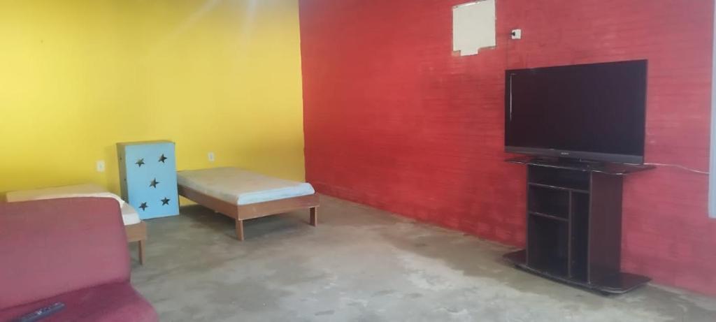 sala de estar con TV y pared roja en Hostel e Pousada Israel en Rio Branco