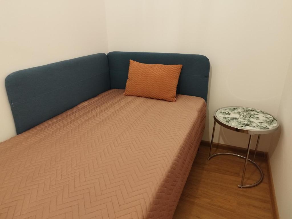 Villa Natali Warszawa في وارسو: سرير مع وسادة وطاولة جانبية