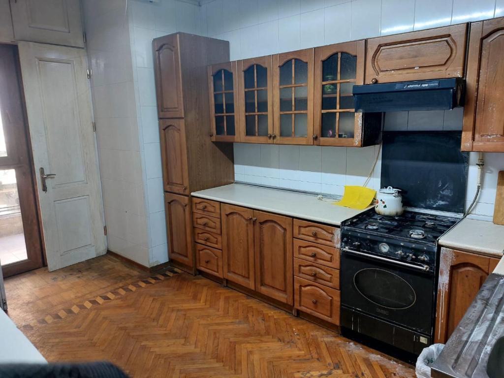 eine Küche mit Holzschränken und einem schwarzen Herd in der Unterkunft F & A APARTMENT in Baku
