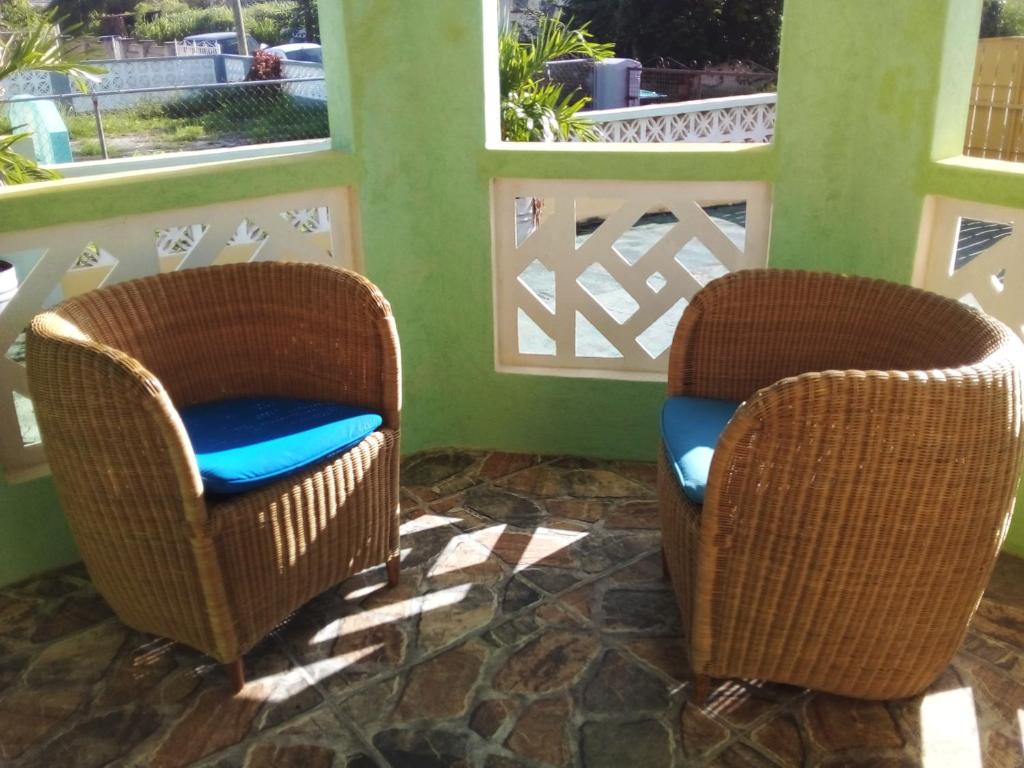 two wicker chairs sitting in a room with windows at Palm View Room 1 in Christ Church
