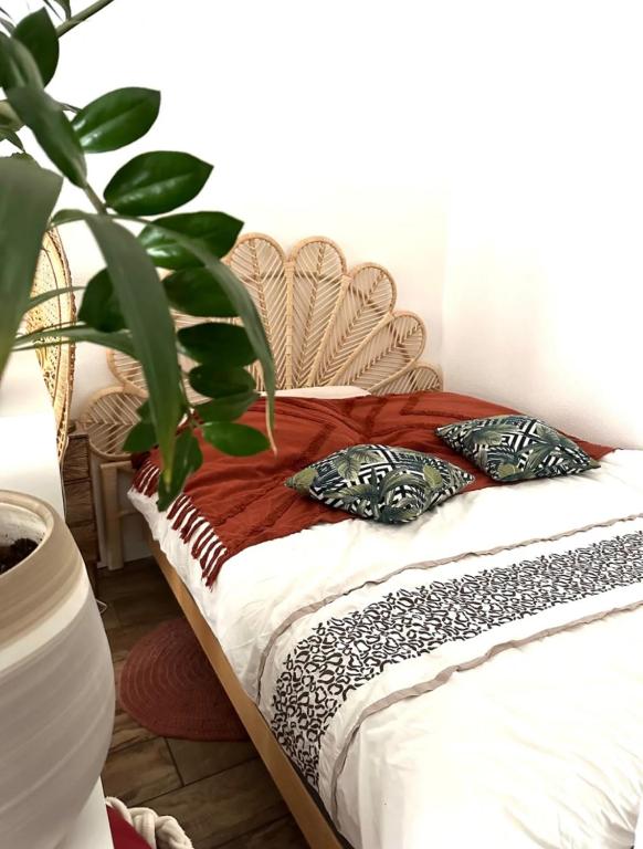 - un lit avec des oreillers et une plante dans la chambre dans l'établissement Joli T1 bis 15 min à pied du lac, au Bourget-du-Lac
