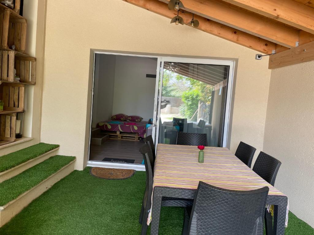 einen Tisch und Stühle auf einer Terrasse mit grünem Gras in der Unterkunft Studio tout équipé avec jacuzzi in Saint-Didier