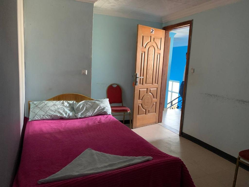 1 dormitorio con 1 cama con sábanas moradas y puerta en AM Guest House en Kitimē