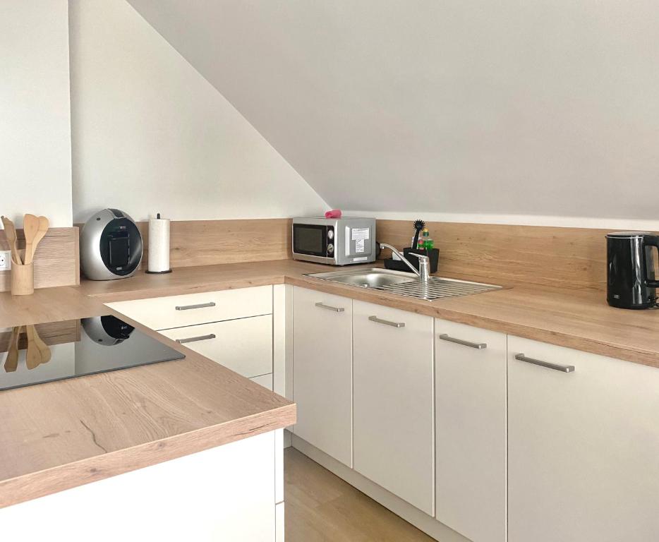 cocina blanca con fregadero y microondas en CITYNA Apartment Bielefeld - Late Check-Out, en Bielefeld