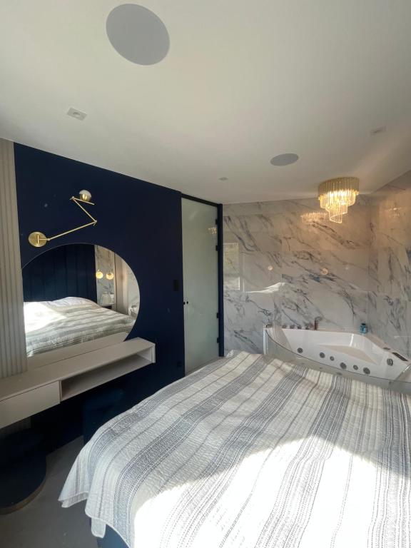 1 dormitorio con 1 cama con espejo y bañera en Apartament LUNA z jacuzzi Premium na Mazurach, en Ełk