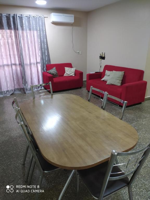 un soggiorno con tavolo e divano rosso di Amplio apartamento a pasos de los principales centros de compras a Ciudad del Este