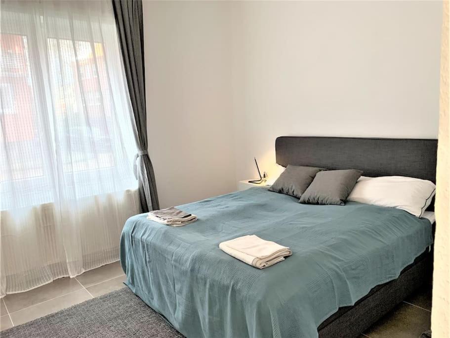 sypialnia z łóżkiem z niebieskim kocem i oknem w obiekcie Stilvoll eingerichtete Wohnung in Essen-Südviertel w Essen