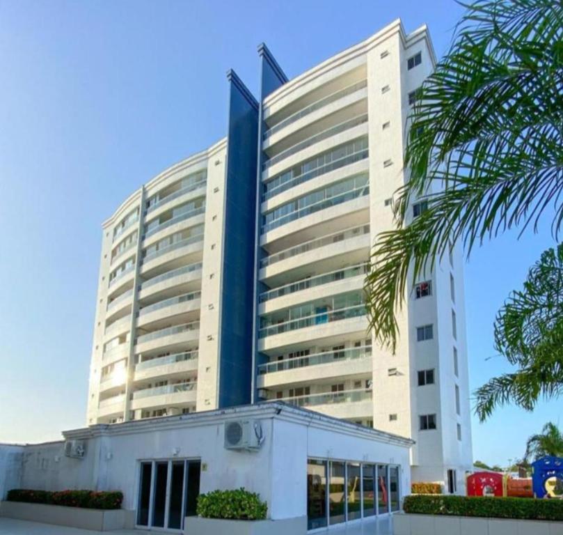 un grand bâtiment blanc avec un palmier en face dans l'établissement APARTAMENTO LUXUOSO A 1KM DA LITORÂNEA, à São Luís