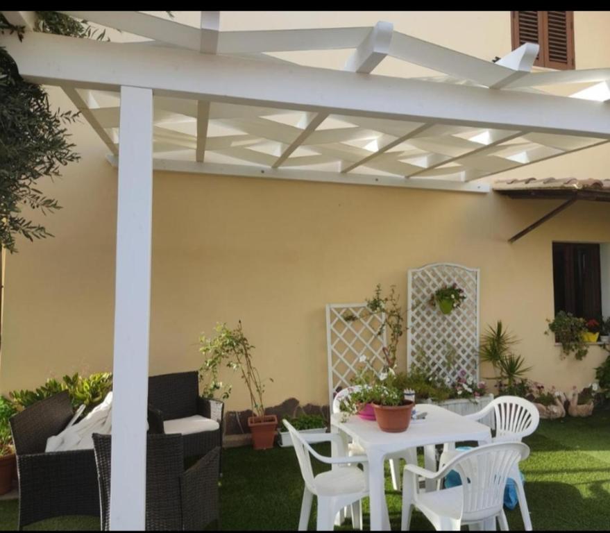 a patio with a white pergola and tables and chairs at Domo Is Domus in SantʼAnna Arresi