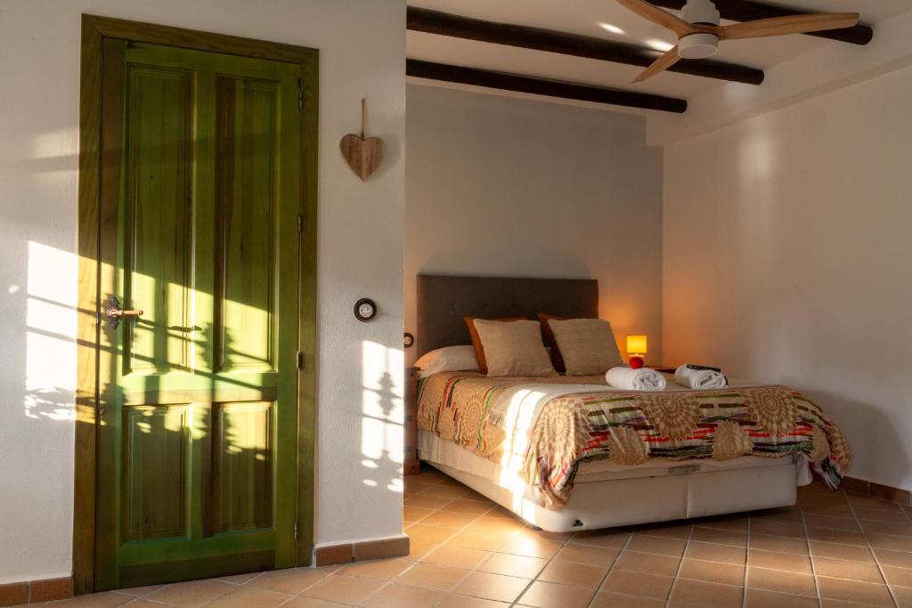 - une chambre avec un lit et une porte verte dans l'établissement El Pinsapo Casa Rural, à Cuevas del Becerro