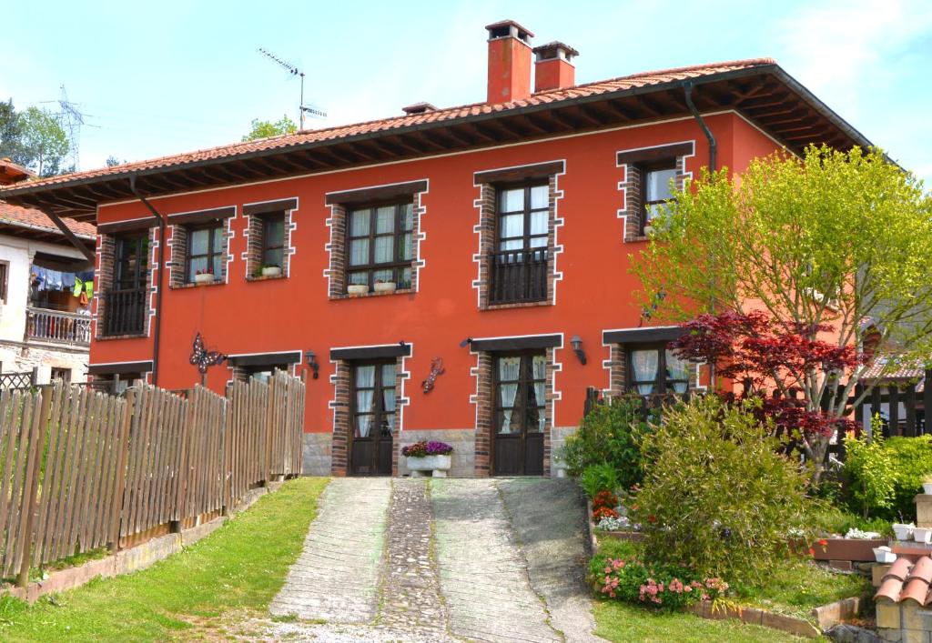 une maison rouge avec une clôture devant elle dans l'établissement Apartamentos Rurales Piedrafita, à Llenín