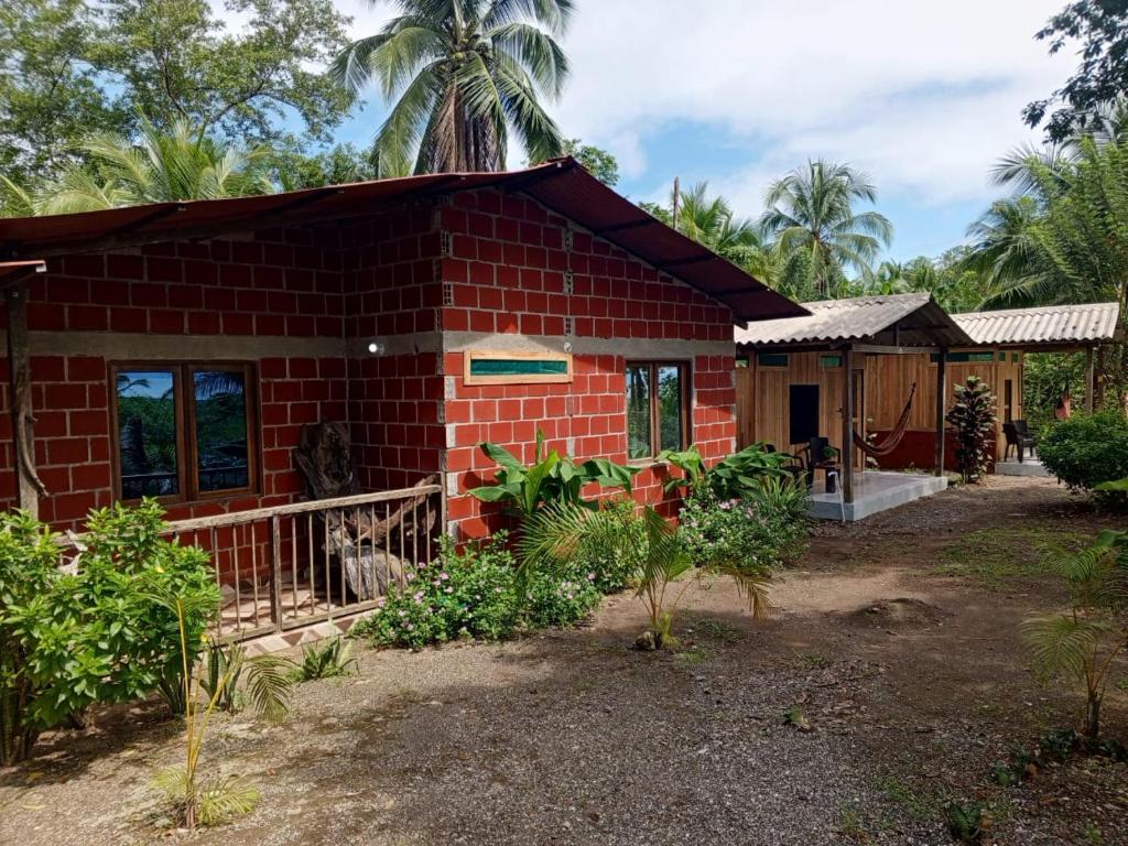 ein kleines rotes Backsteinhaus mit einer Veranda in der Unterkunft Cabañas Zona Verde in Nuquí